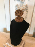 Black velvet jewelry display with aged metal rose and barn wood base