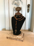 Black velvet jewelry display with aged metal rose and barn wood base