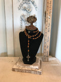 Black velvet jewelry display with aged metal rose and barn wood base